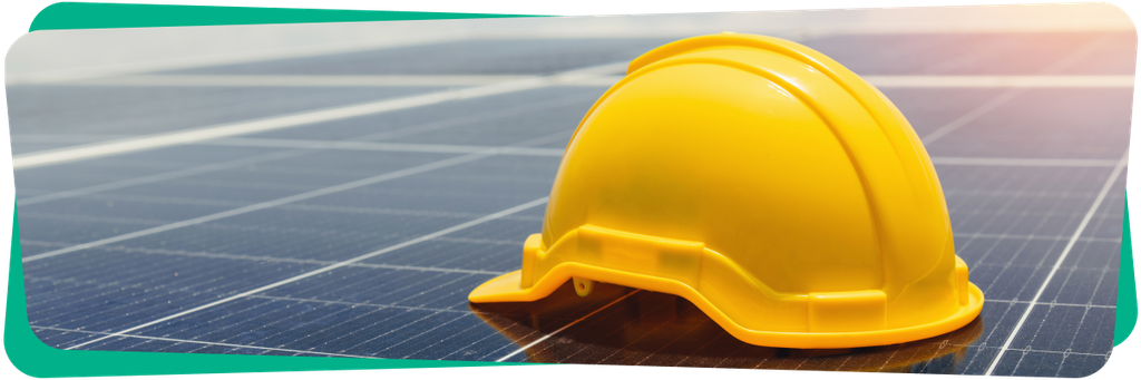 Yellow hard hat resting on solar panels under sunlight, highlighting safety in renewable energy environments.